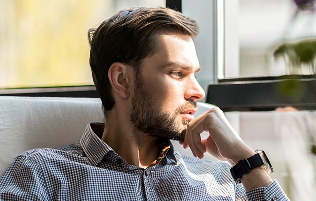 Junger Mann schaut nachdenklich in die Ferne