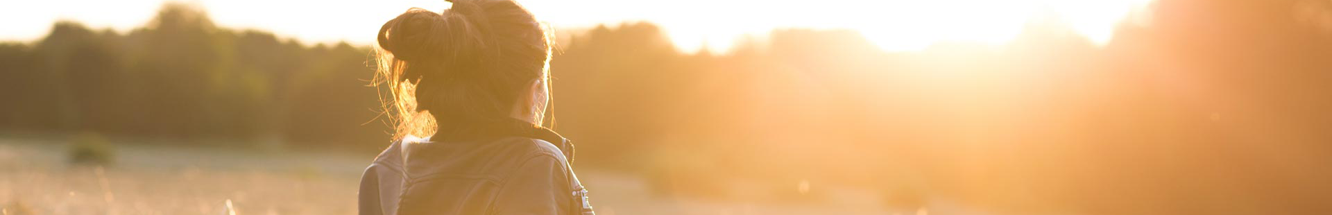 Junge Frau auf Stoppelfeld schaut in die Abendsonne