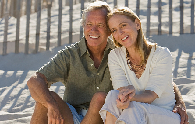 Verliebtes Paar am Strand sitzend, lächelnd