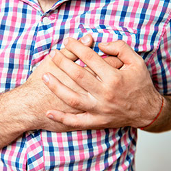Mann, beide Hände vor Schmerz an die Brust haltend