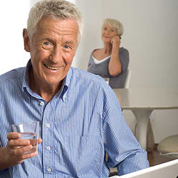 Mann mit Glas Wasser bei der Medikamenteneinnahme