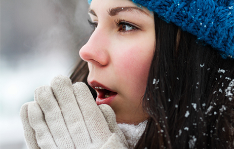 Junge Frau mit Handschuhen vorm Gesicht