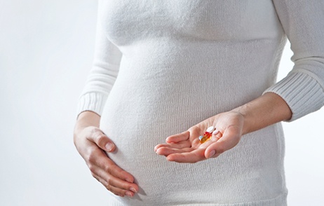 Schwangere Frau mit Medikamenten i9n der Hand