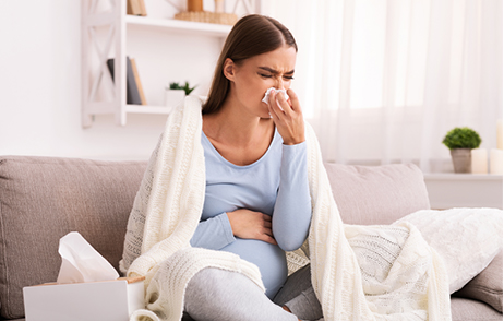 Schwangere, sich schnäutzende junge Frau