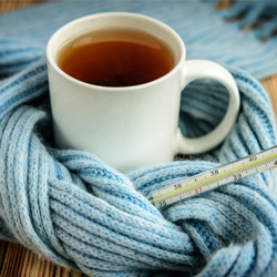 Teetasse und Fieberthermometer ind Schal gewickelt