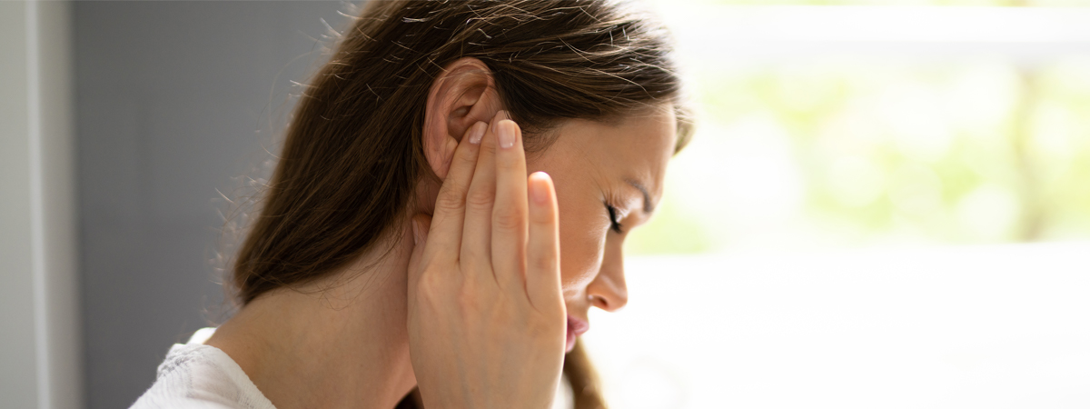 Frau fasst sich ans Ohr