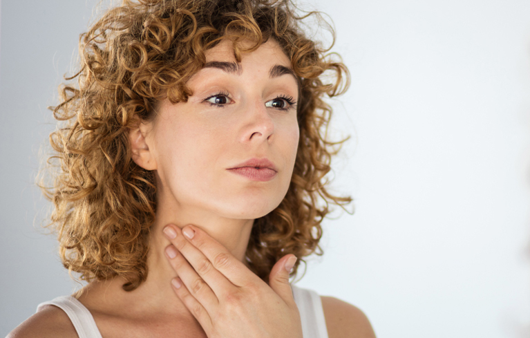 Junge Frau greift sich an den Hals