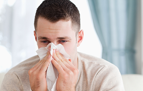 Mann schneutzt sich die Nase