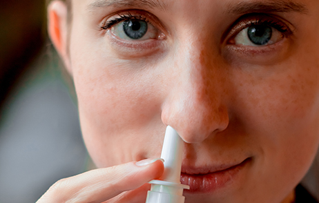 Junge Frau verwendet Nasenspray ohne Konservierungsstoffe