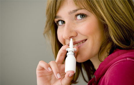 Frau benutzt Nasenspray