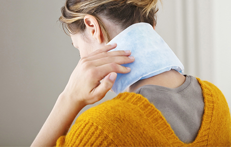 Frau mit Wärmepad im Nacken