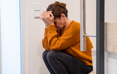 Frau mit depressiver Stimmung, knieend, Kopf auf Hände gestützt