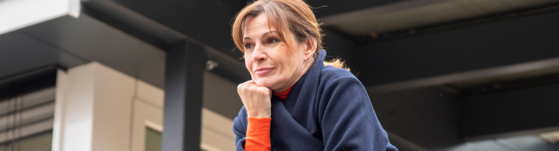 Frau schaut nachdenklich am Balkon stehend