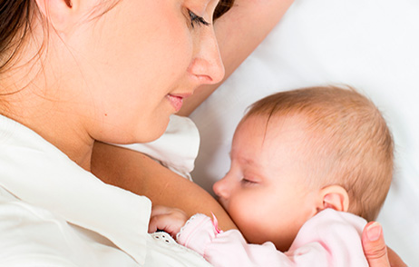 Mama stillt ihr Baby seitlich liegend