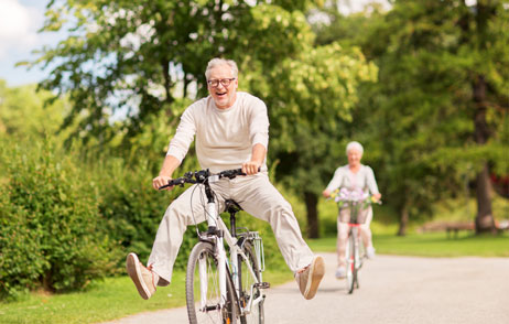 Mann fährt lächelnd Fahrrad und streckt die Beine aus