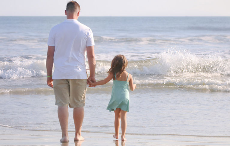 Vater geht mit Tochter am Strand spazieren