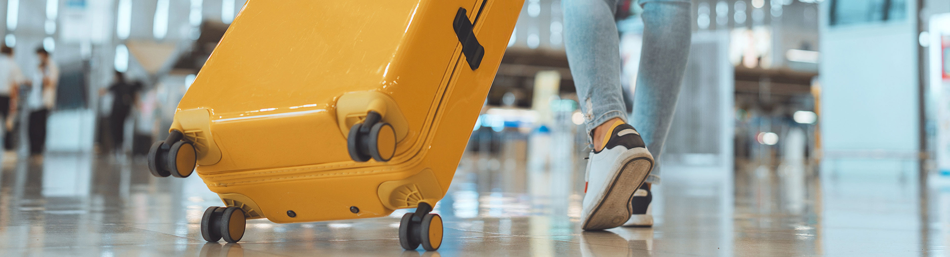 knallgelber Reisekoffer auf Rollen wird gezogen