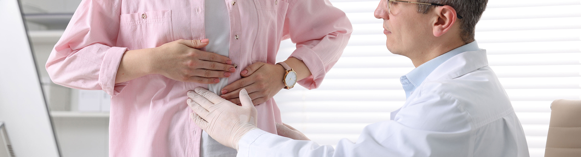 Frau mit Bauchschmerzen bei Untersuchung, Arzt tastet ab