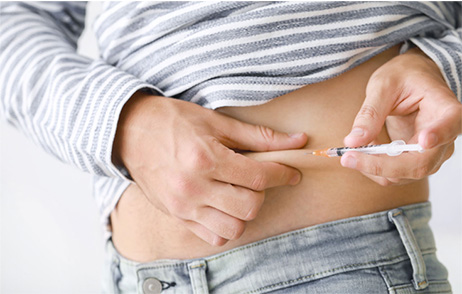 Frau spritzt sich selbst in die Bauchfalte