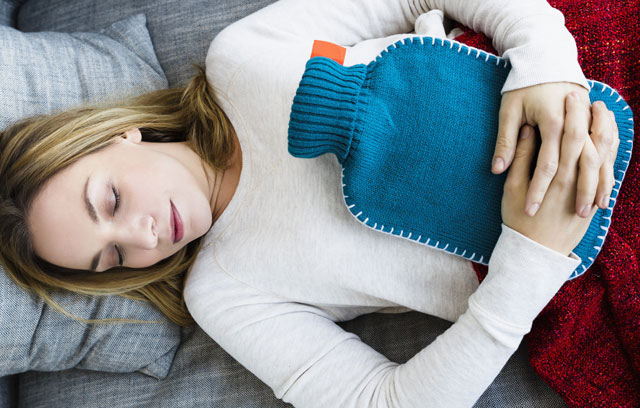 Ein Frau hat sich mit einer Wärmflasche hingelegt