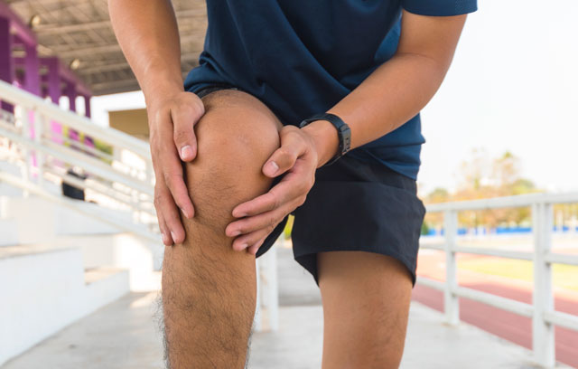 Mann hält mit Händen sein Knie beim Sport