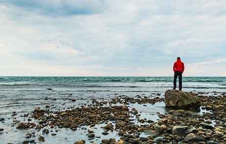 Mann am Strand blickt aufs Meer