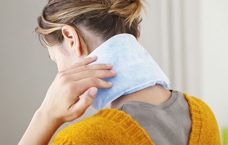 Eine Frau hat ein Wärmepad auf dem Nacken