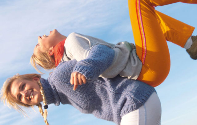 Zwei Frauen haken sich Rücken an Rücken ein und lachen
