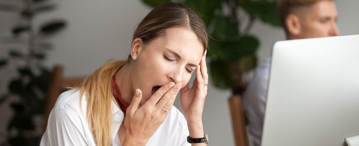 Frau gähnt vor Computer