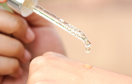 Pipette tropft auf Handrücken