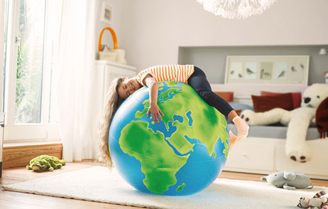 Kind liegt auf einem riesigen aufgeblasenen Erdball