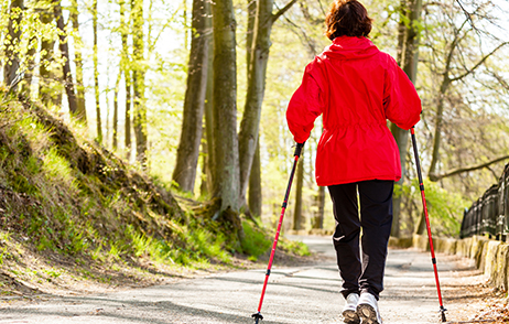 Bewegung im Alltag: Frau geht mit Stöcken durch den Wald