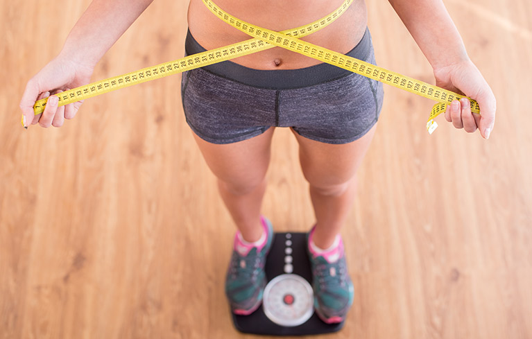 Erfolgreich Abnehmen: Person hält sich Massband um die Taille
