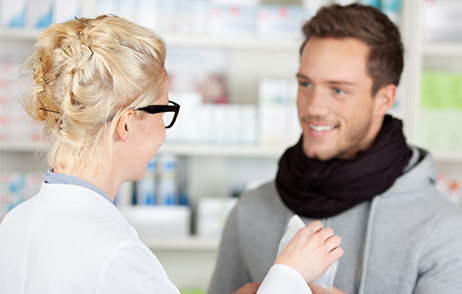 Junger Mann mit Halsschmerzen in Apotheke