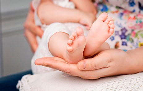 Frau mit Baby auf dem Arm, Füßchen in der Handfläche