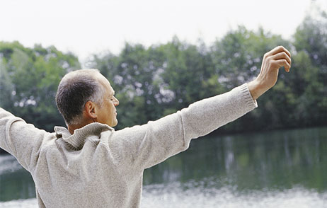 Mann am See, streckt die Arme 