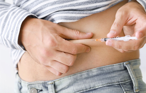 Frau spritzt sich selbst in die Bauchfalte