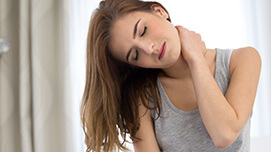 Junge Frau greift sich an den Nacken