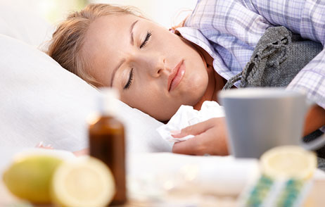 Frau liegt mit Grippe im Bett und schläft