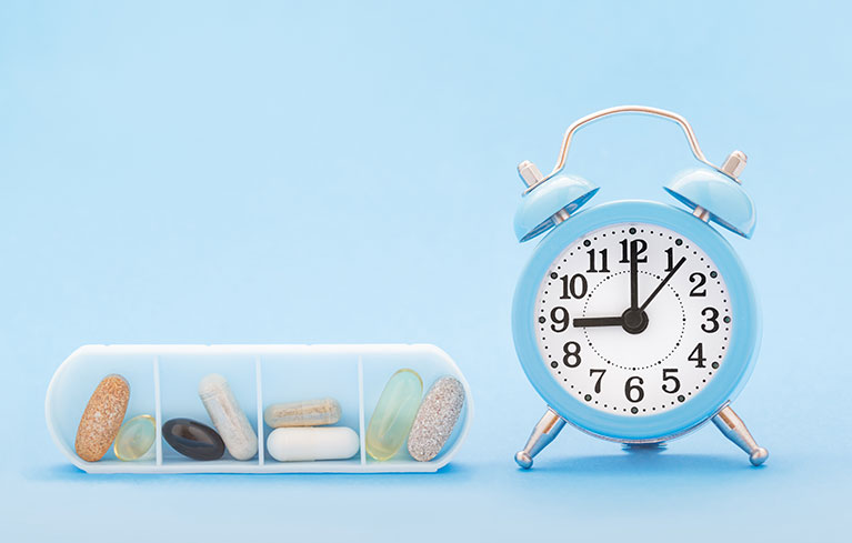 Medikamente neben einem Wecker