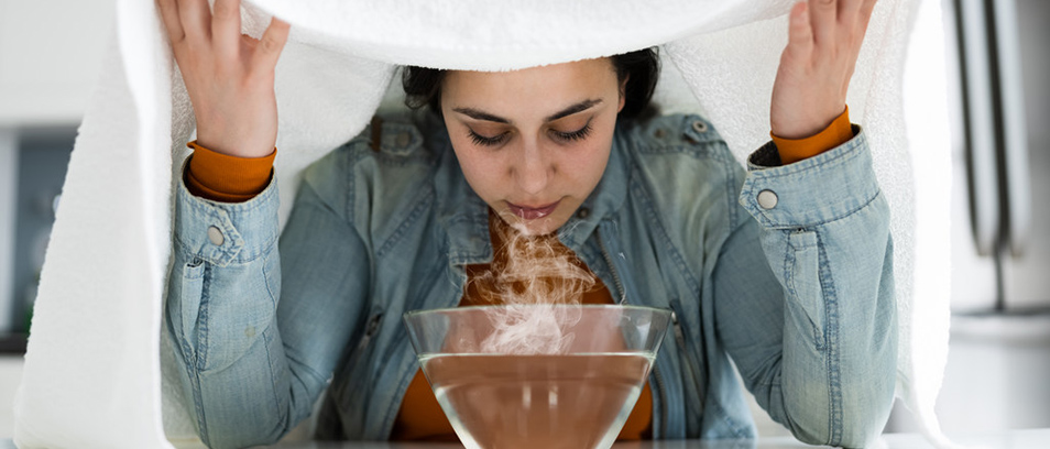 Frau unterm Handtuch atmet Dämpfe ein