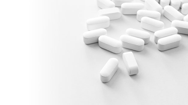 Die Abbildung zeigt einige teilbare Tabletten, die auf einem Tisch liegen. 