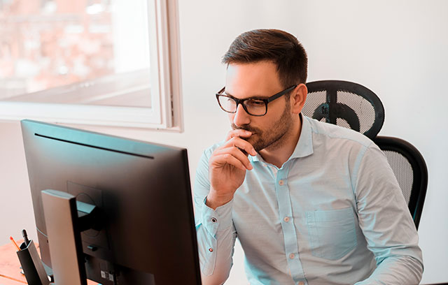 Mann schaut fragend auf einen Computer-Bildschirm