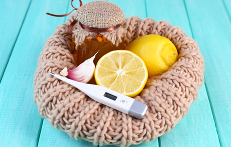 Fieberthermometer, Honig, Zitrone und Knoblauch auf einem Wollkissen