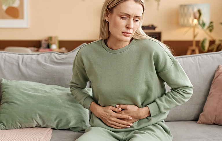 Frau fasst sich mit beiden Händen an den Bauch