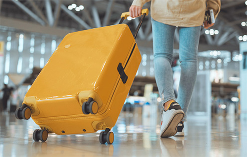 knallgelber Reisekoffer auf Rollen wird gezogen