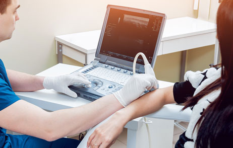Diagnose Schleimbeutelentzündung Arzt untersucht den Ellenbogen einer Patientin mit dem Ultraschall