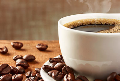 Kaffee vertreibt den Schmerz Eine Tasse Kaffee und Kaffeebohnen