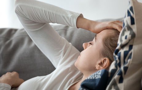 Katerkopfschmerzen Junge Frau auf dem Sofa mit Kopfschmerzen